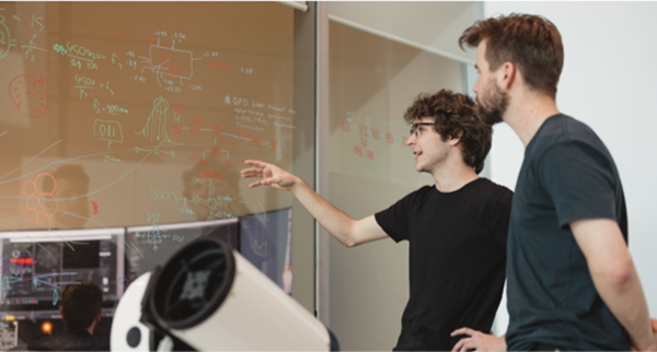 Student showing another student equations on whiteboard