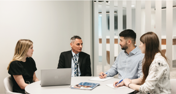 3 Students sitting at table with mentor