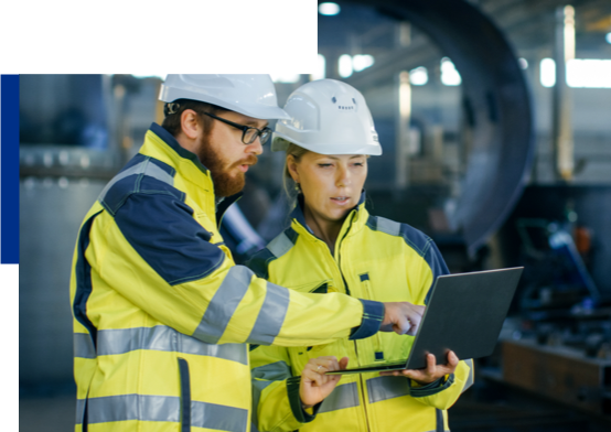 Man and woman in hi-vis outfit on worksite looking at laptop