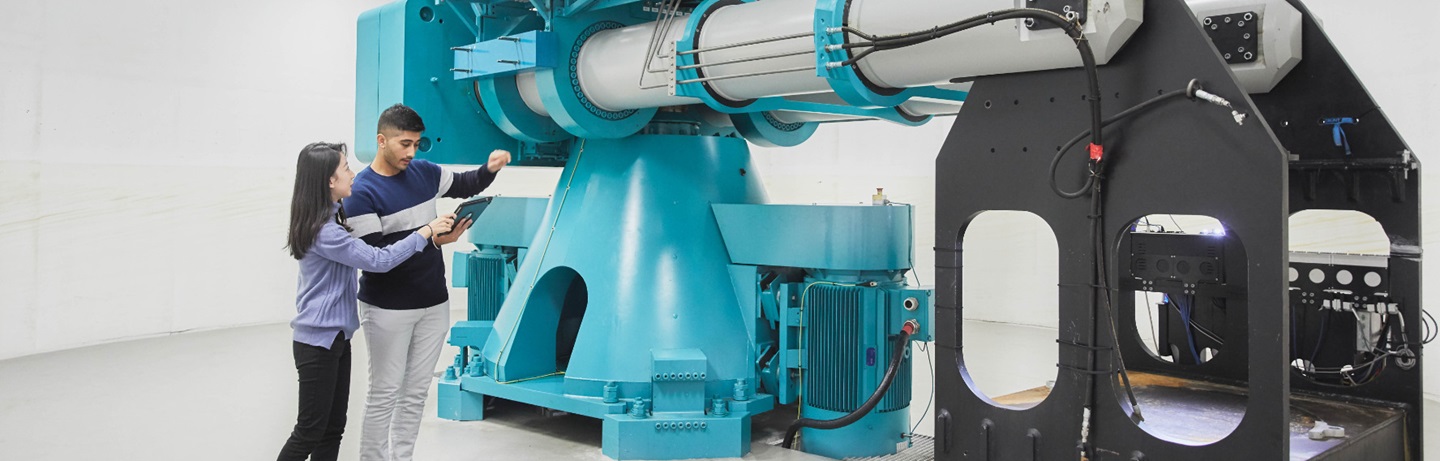Two students standing in front of the geotechnical centrifuge